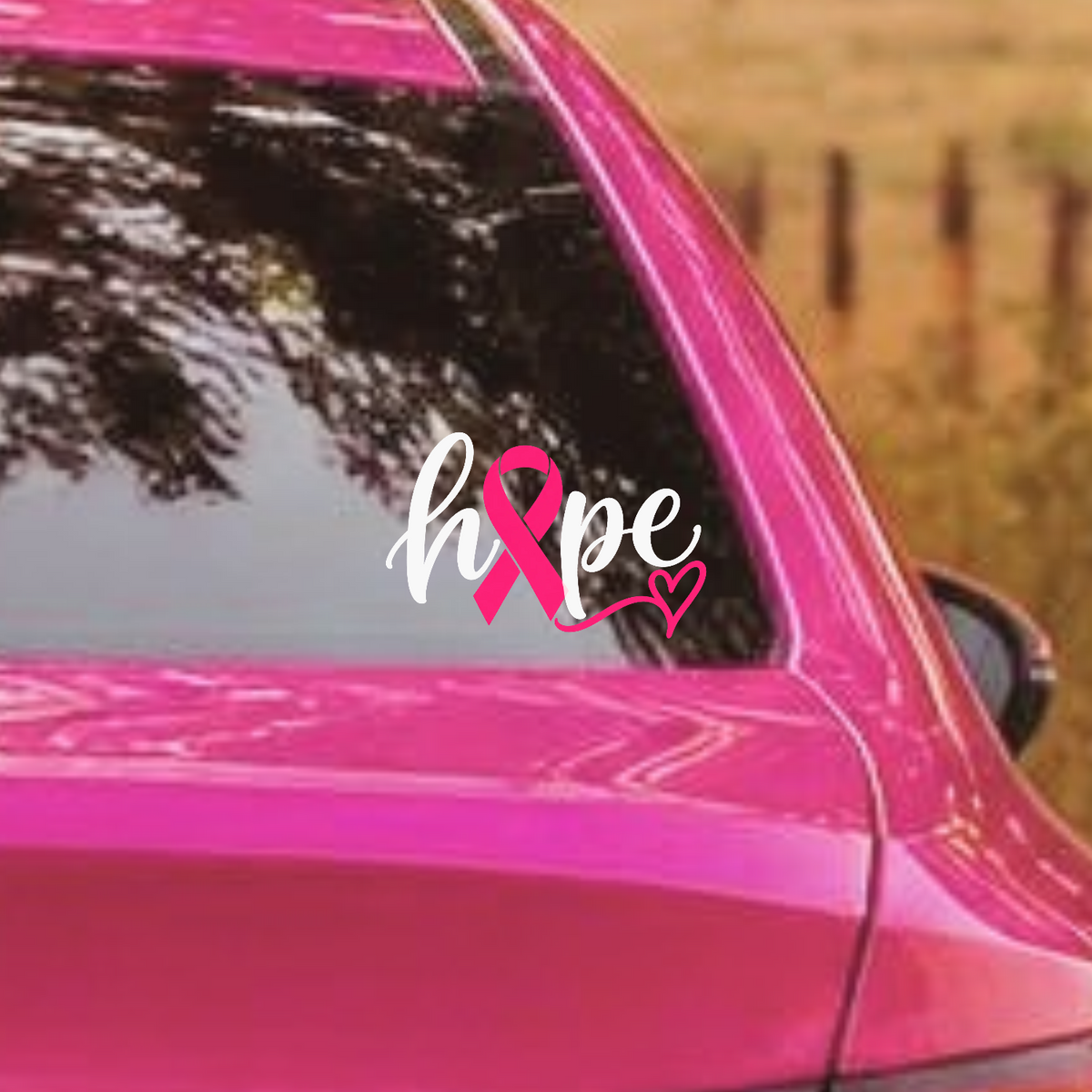 A white vinyl decal spelling 'hope' with a pink awareness ribbon and small heart, shown applied to the rear window of a bright pink car in an outdoor setting.